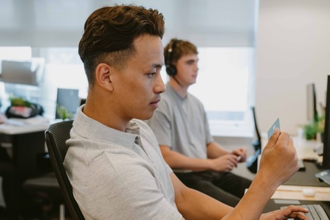 Employee taking a look at his Payhawk corporate card, contemplating how it simplified their bank reconciliation processes. 